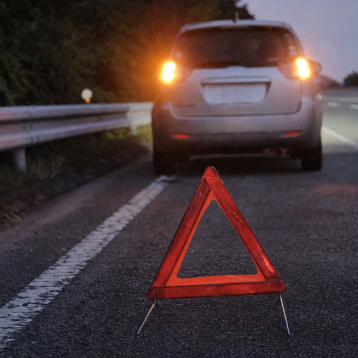 薄暮の高速道路の路肩に停車した車と三角表示板